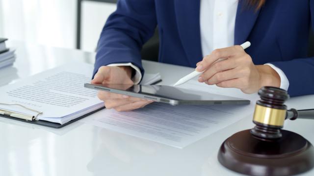 Individual at table looking through paperwork with gavel.