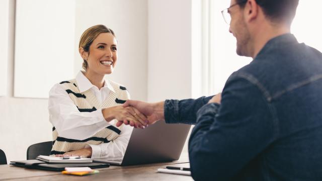 Two people shaking hands at a desk