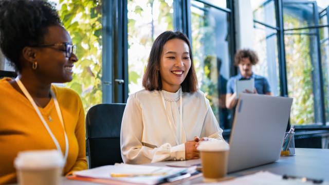 Adult students sitting at a table looking at a laptop