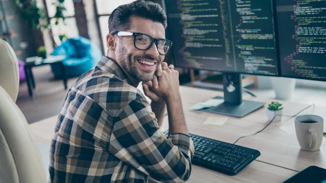 Individual smiling in front of computer screen.