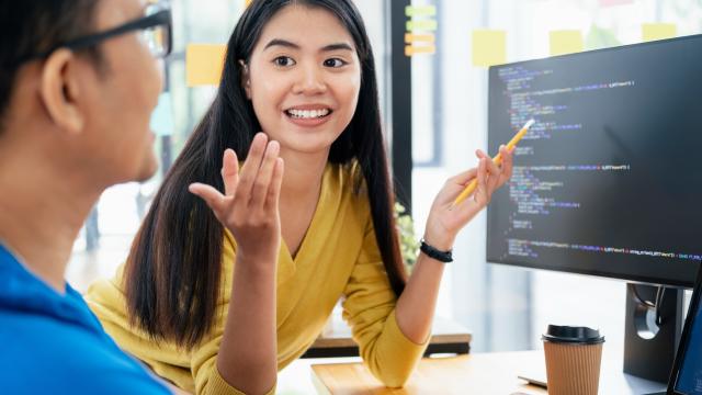two students talking and looking at a computer screen