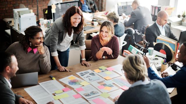 A group collaborating at a table at work. Everyone is cheerful