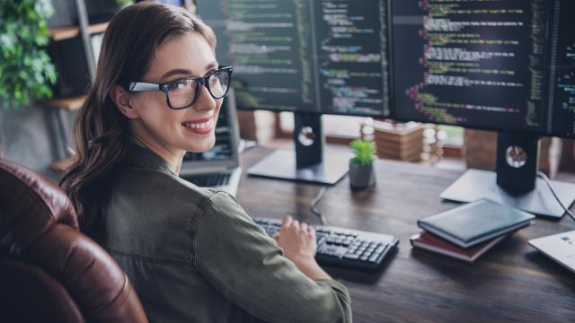 Computer Programmer looking away from a computer screen smiling