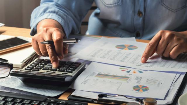 person typing on a calculator and looking at a bill