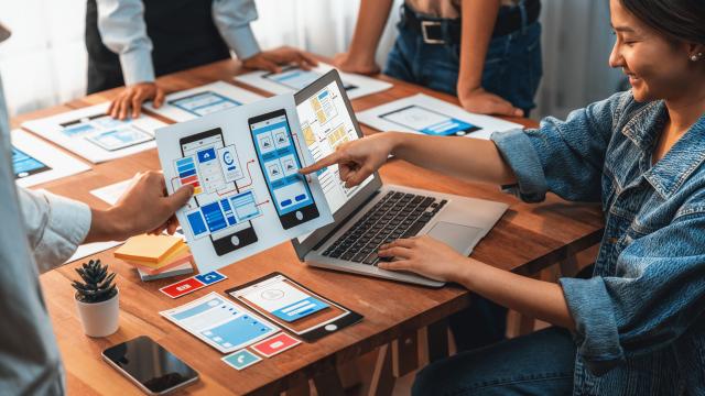 People sitting at a table looking at a web design document